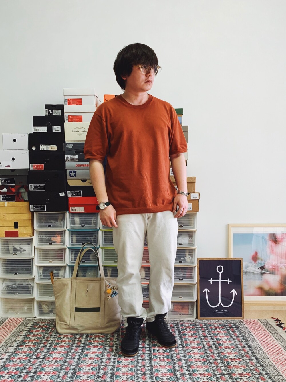 オレンジ系のニット/セーター、ホワイト系のデニムパンツ、ブラック系のスニーカーを着用したメンズの夏コーディネートの1枚目の写真