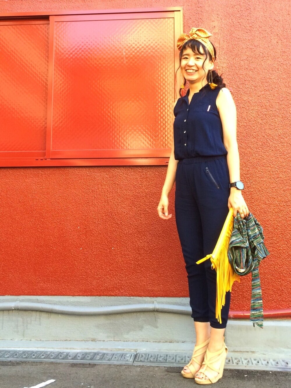 ベージュ系のサンダル、ブルー系のつなぎ/オールインワン、イエロー系のクラッチバッグを着用したレディースの夏コーディネートの1枚目の写真