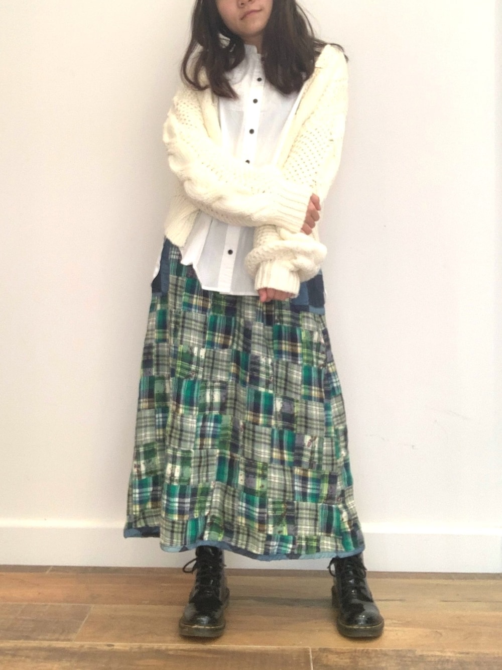 グリーン系のスカート、ホワイト系のシャツ/ブラウス、ブラック系のブーツを着用したレディースの秋コーディネートの1枚目の写真
