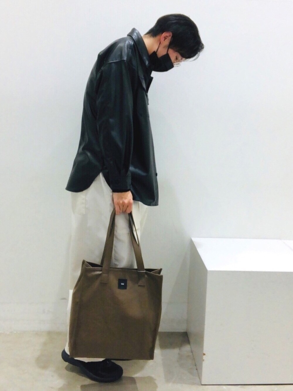 ブラック系のブルゾン、ホワイト系のその他パンツ、ベージュ系のトートバッグを着用したメンズの冬コーディネートの1枚目の写真