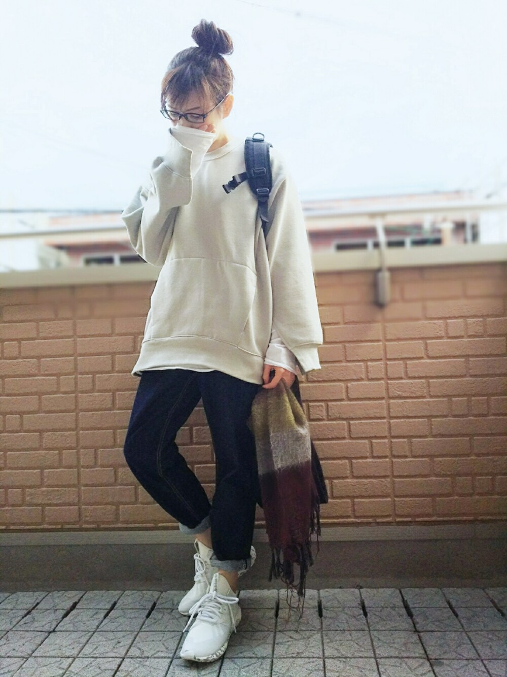 グレー系のTシャツ/カットソー、ブラック系のバックパック/リュック、ブルー系のデニムパンツを着用したレディースの冬コーディネートの1枚目の写真