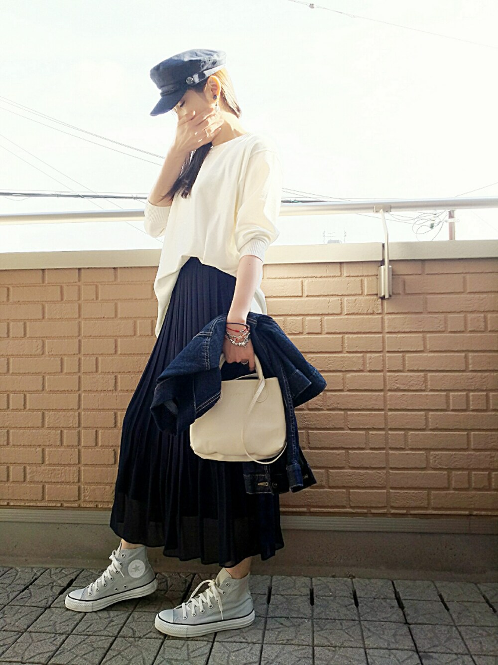 ブルー系のスカート、グレー系のスニーカー、ホワイト系のニット/セーターを着用したレディースの春コーディネートの1枚目の写真