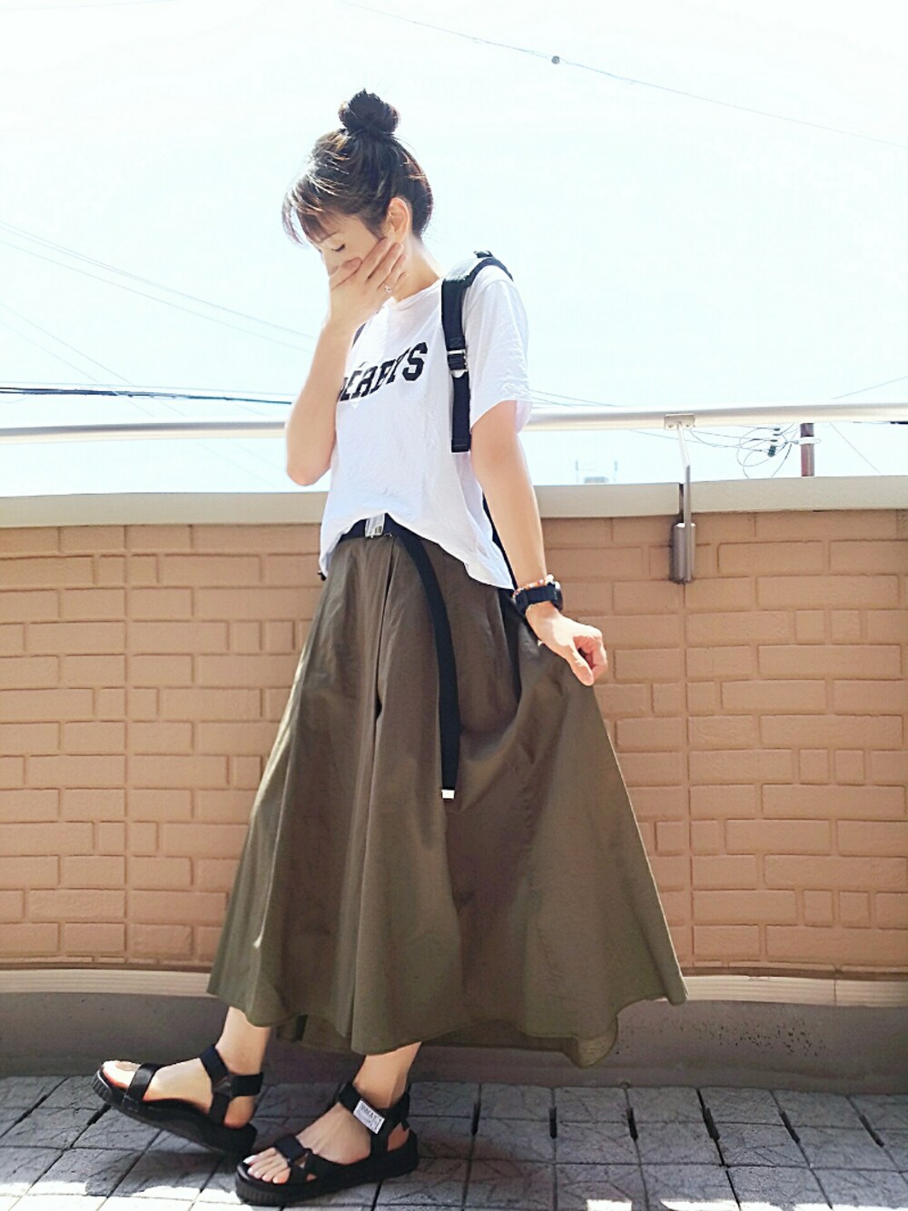 グリーン系のスカート、ブラック系のサンダル、ブラック系のバックパック/リュックを着用したレディースの夏コーディネートの1枚目の写真