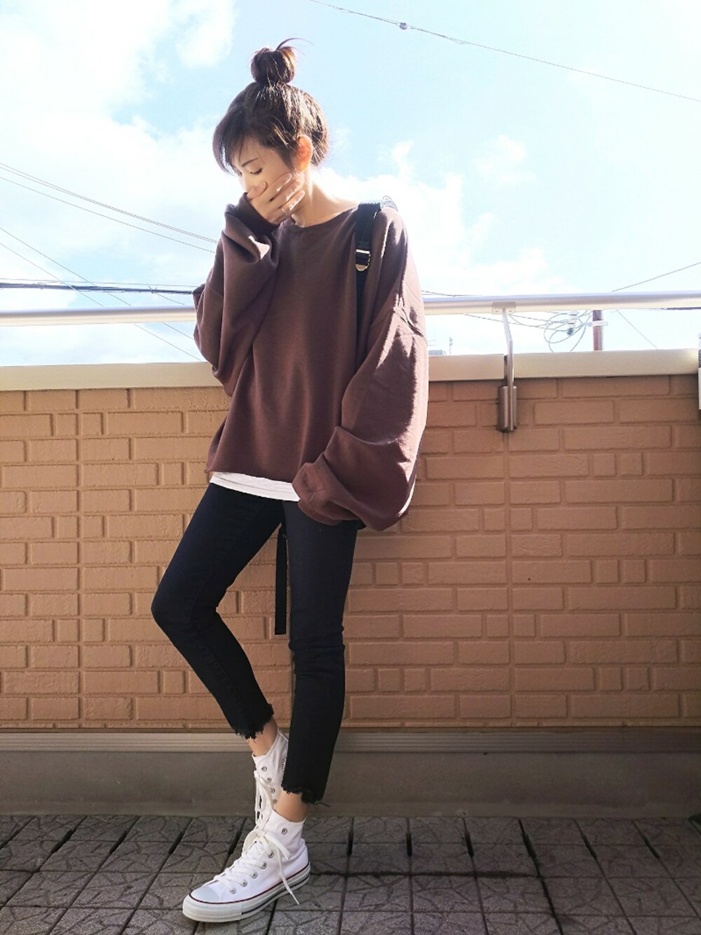 ブラック系のバックパック/リュック、ブラック系のデニムパンツ、ホワイト系のスニーカーを着用したレディースの秋コーディネートの1枚目の写真