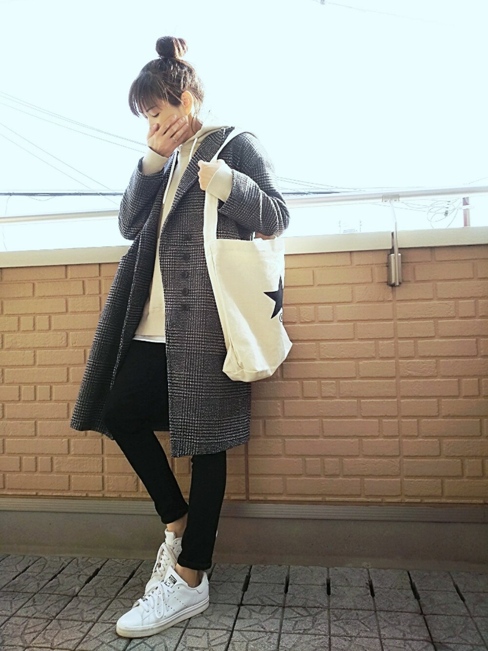 ブラック系のチェスターコート、ホワイト系のトートバッグ、ブラック系のデニムパンツを着用したレディースの秋コーディネートの1枚目の写真