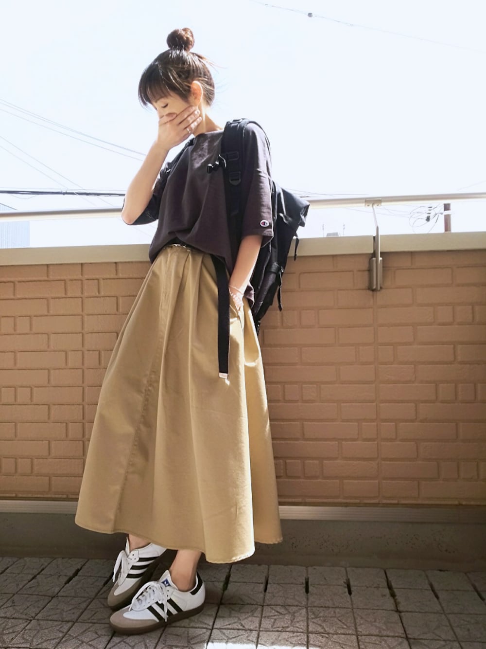 ブラック系のバックパック/リュック、ブラック系のTシャツ/カットソー、ベージュ系のスカートを着用したレディースの春コーディネートの1枚目の写真