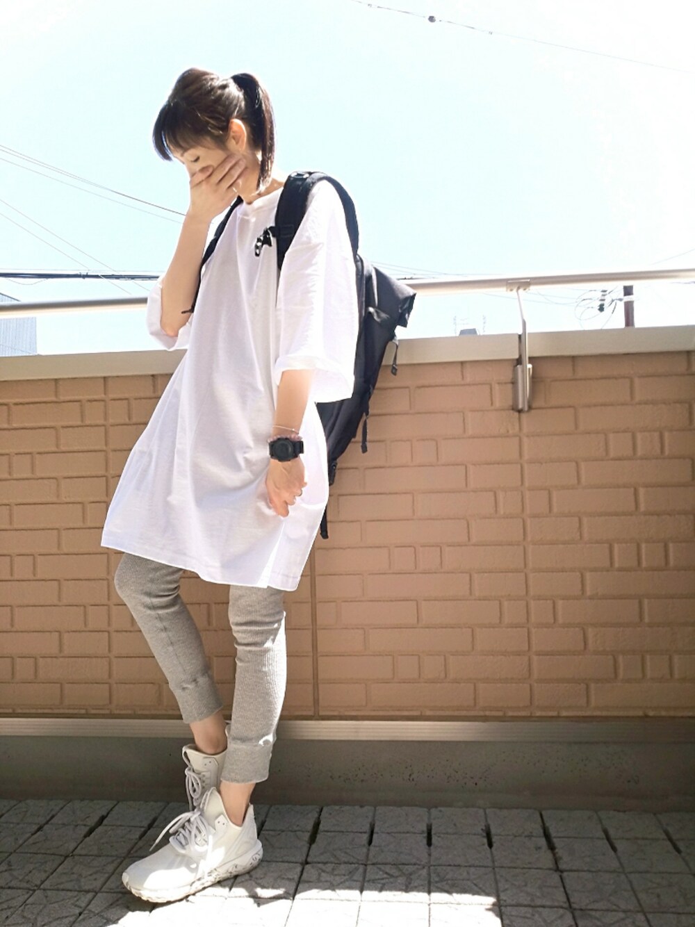 ブラック系のバックパック/リュック、ホワイト系のTシャツ/カットソー、ホワイト系のスニーカーを着用したレディースの春コーディネートの1枚目の写真