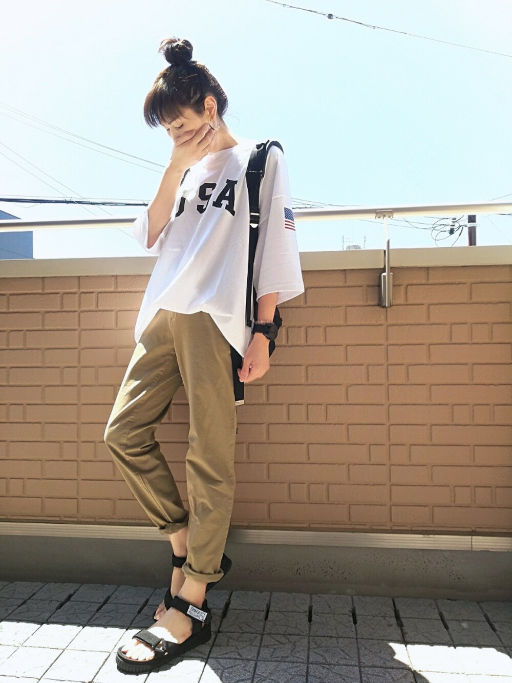 ブラック系のバックパック/リュック、ブラック系のサンダル、ベージュ系のチノパンツを着用したレディースの夏コーディネートの1枚目の写真