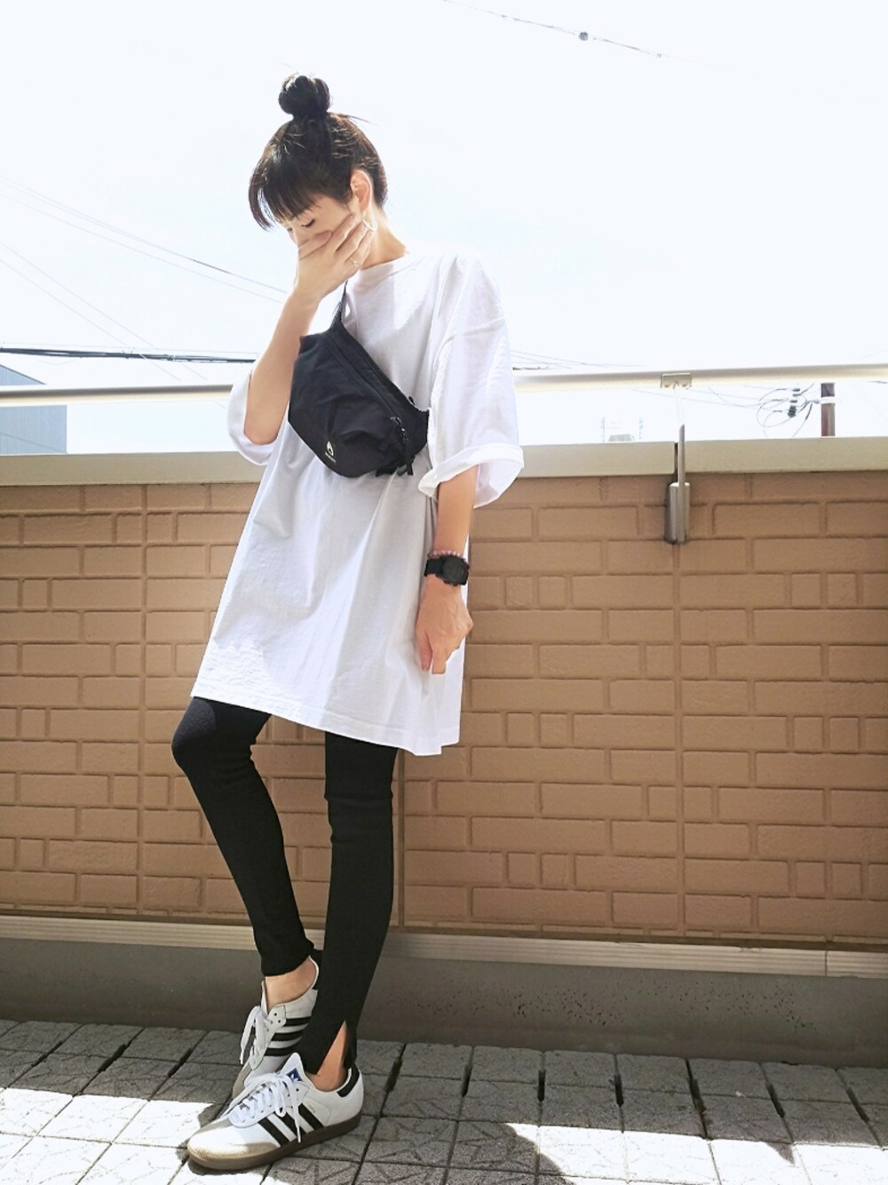 ホワイト系のスニーカー、ブラック系のボディバッグ/ウエストポーチ、ホワイト系のTシャツ/カットソーを着用したレディースの夏コーディネートの1枚目の写真