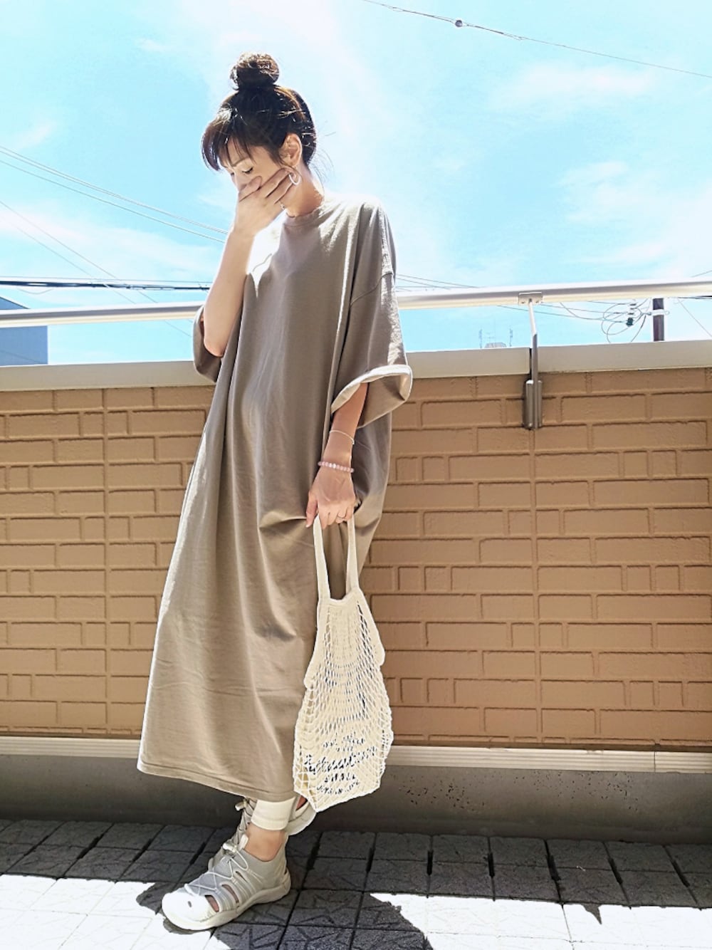 ベージュ系のワンピース、ホワイト系のサンダル、ホワイト系のイヤリングを着用したレディースの夏コーディネートの1枚目の写真