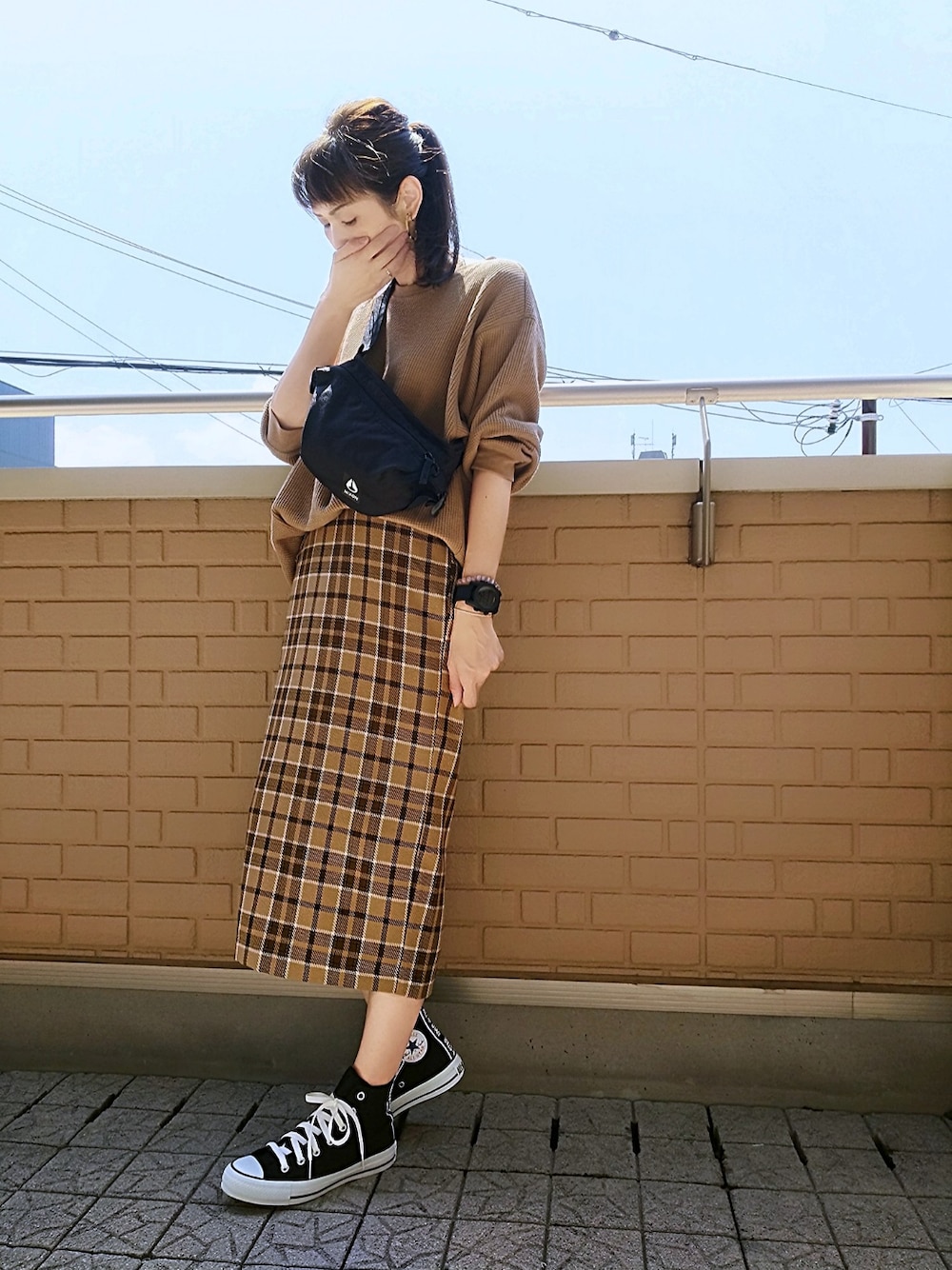 ブラック系のスニーカー、ベージュ系のスカート、ベージュ系のTシャツ/カットソーを着用したレディースの夏コーディネートの1枚目の写真