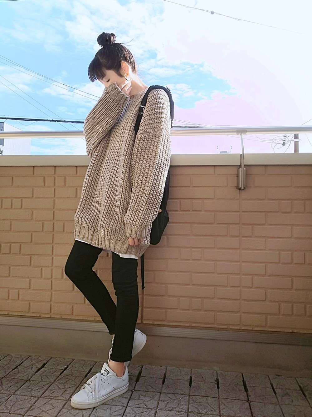 ベージュ系のニット/セーター、ブラック系のデニムパンツ、ブラック系のバックパック/リュックを着用したレディースの秋コーディネートの1枚目の写真