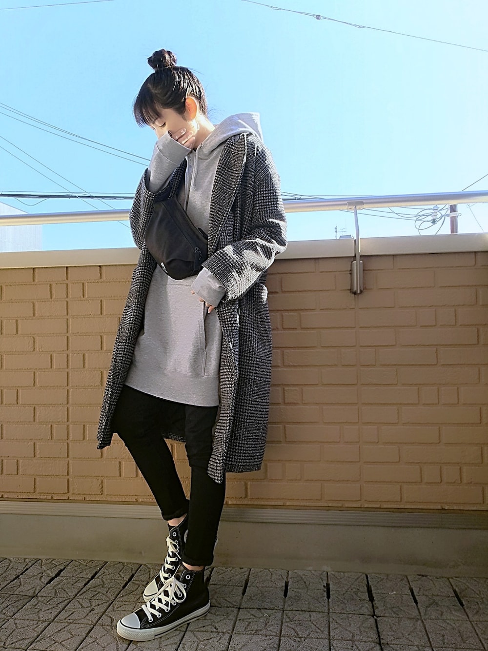 ブラック系のデニムパンツ、ブラック系のスニーカー、ブラック系のチェスターコートを着用したレディースの冬コーディネートの1枚目の写真