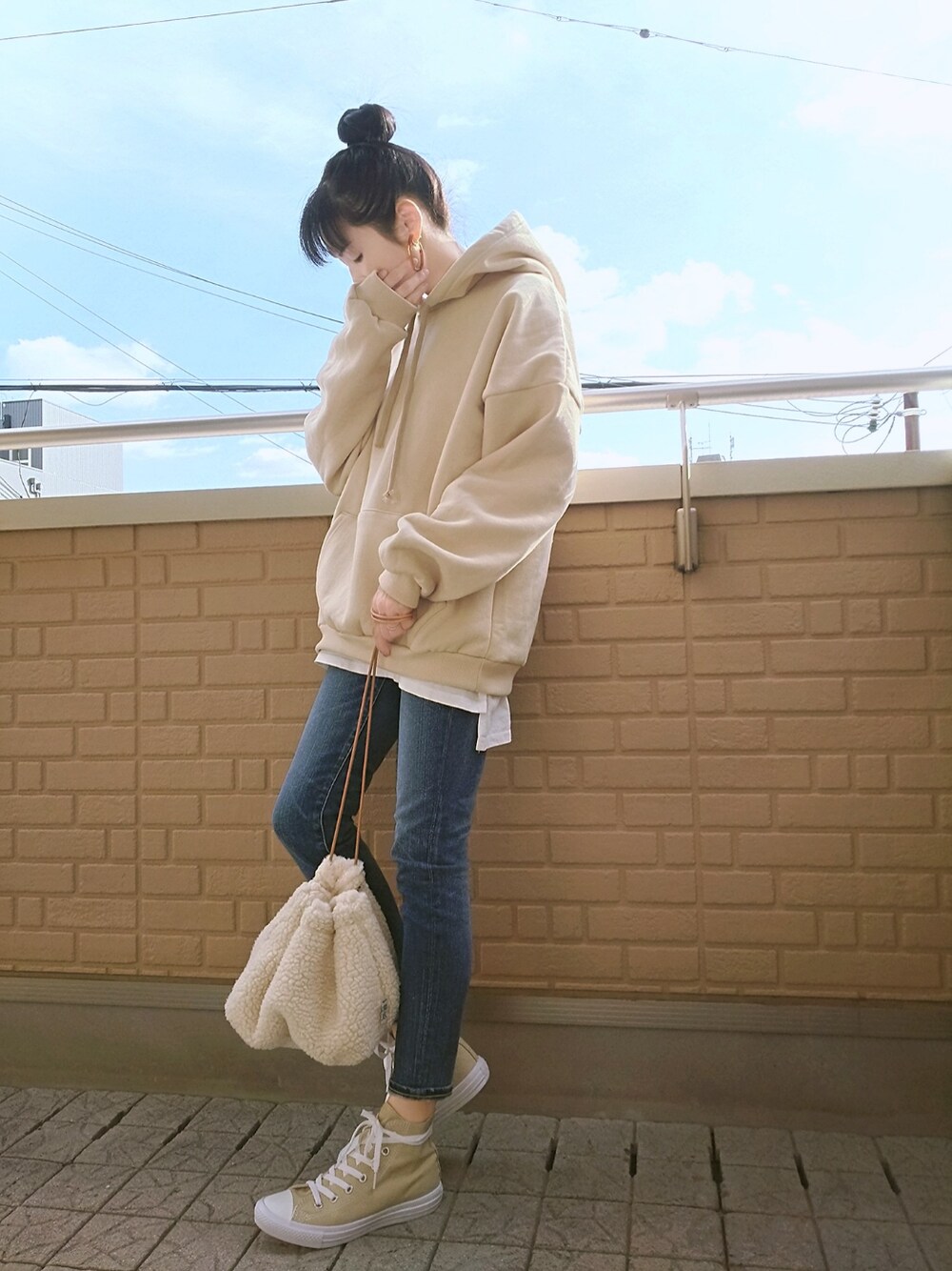 ベージュ系のパーカー、ブルー系のデニムパンツ、ベージュ系のスニーカーを着用したレディースの冬コーディネートの1枚目の写真