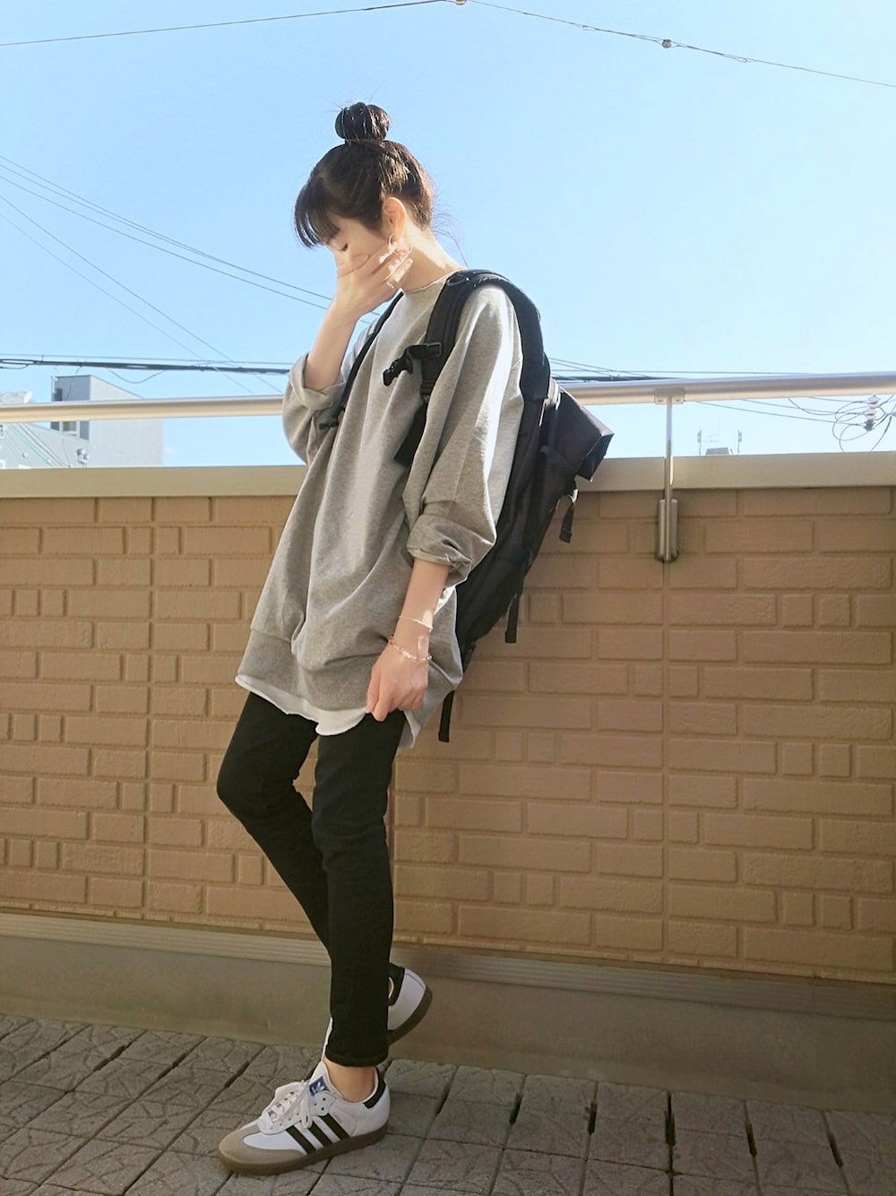 グレー系のスウェット、ホワイト系のスニーカー、ブラック系のデニムパンツを着用したレディースの春コーディネートの1枚目の写真