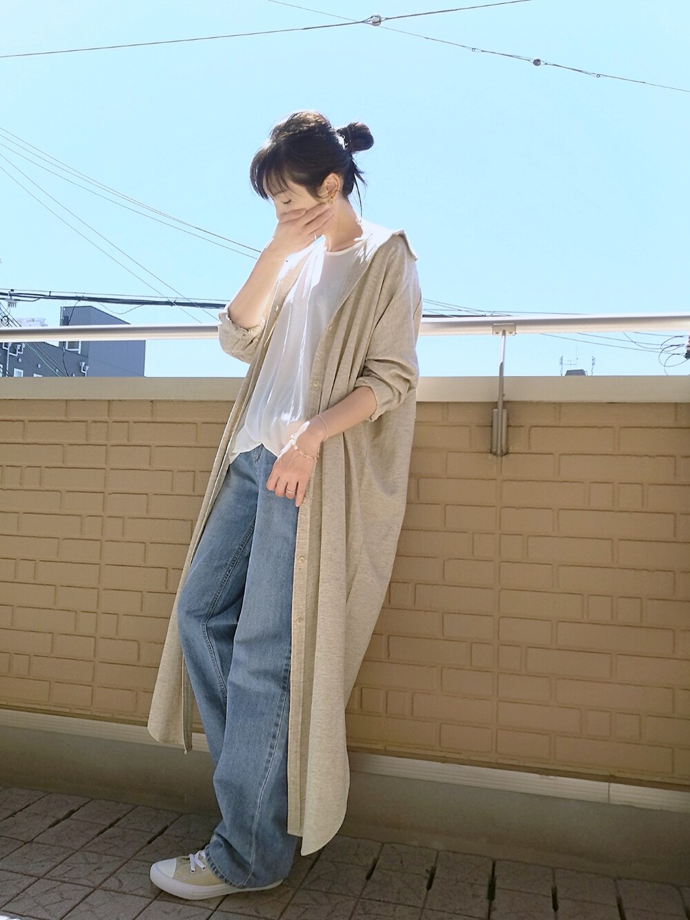 ホワイト系のTシャツ/カットソー、ベージュ系のシャツワンピース、ブルー系のデニムパンツを着用したレディースの春コーディネートの1枚目の写真