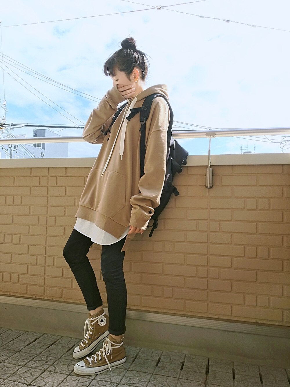 ブラウン系のスニーカー、ベージュ系のパーカー、ブラック系のバックパック/リュックを着用したレディースの秋コーディネートの1枚目の写真