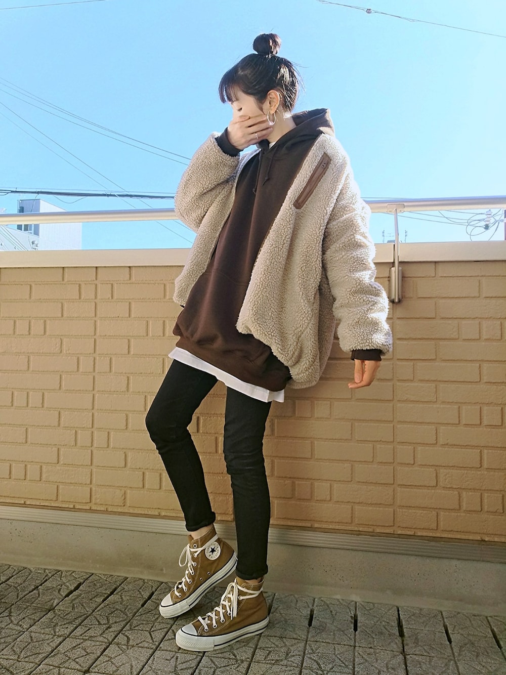ブラウン系のスニーカー、ブラック系のデニムパンツ、ブラウン系のパーカーを着用したレディースの秋コーディネートの1枚目の写真