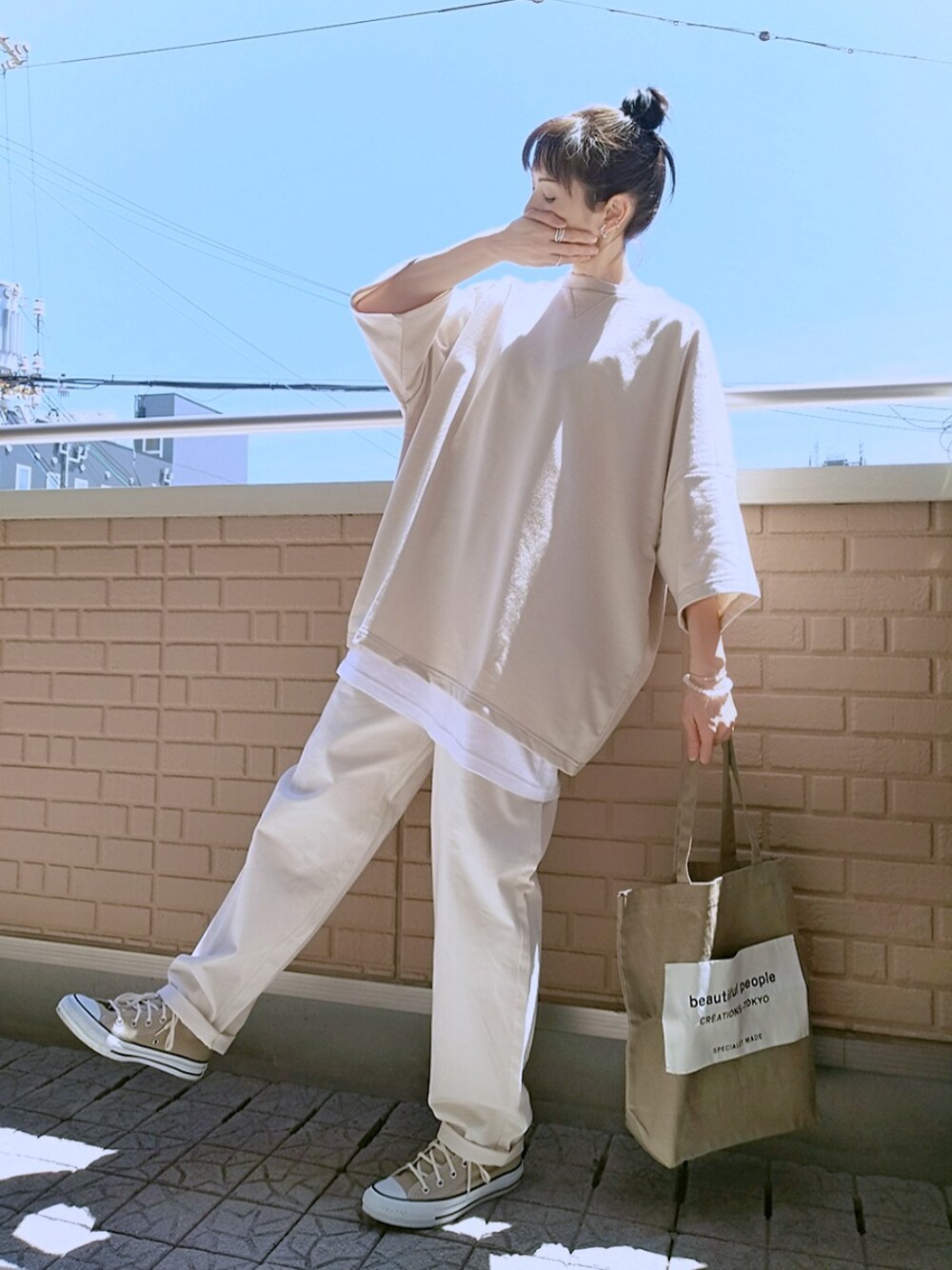 ベージュ系のTシャツ/カットソー、ホワイト系のデニムパンツ、ベージュ系のスニーカーを着用したレディースの春コーディネートの1枚目の写真