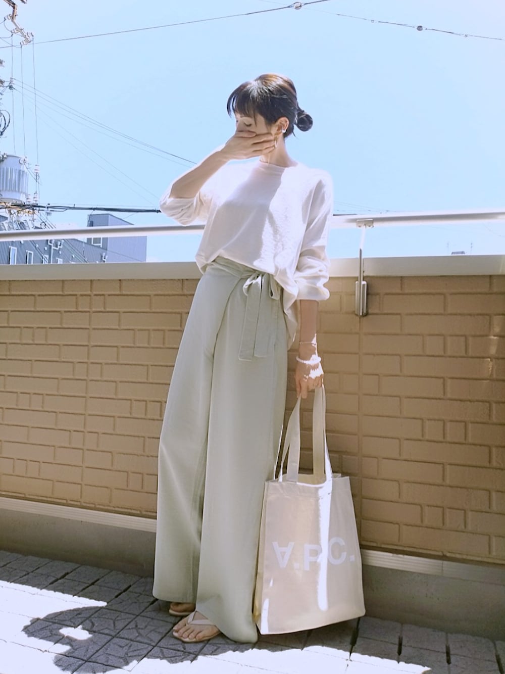 グリーン系のパンツ、ベージュ系のトートバッグ、ベージュ系のサンダルを着用したレディースの夏コーディネートの1枚目の写真