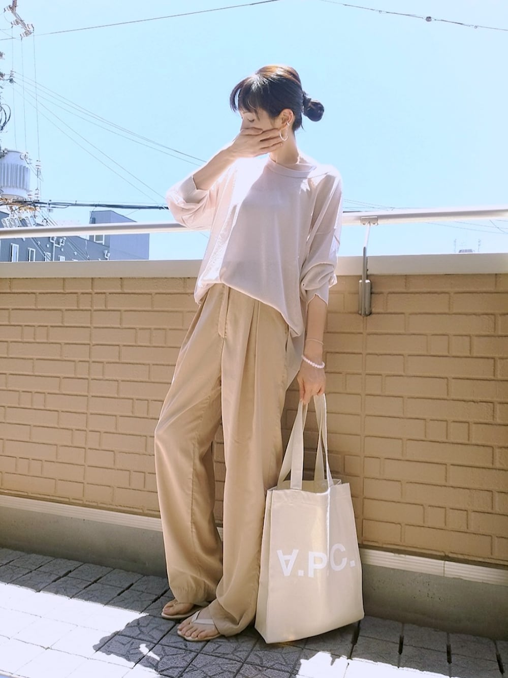ベージュ系のトートバッグ、ホワイト系のキャミソール、ベージュ系のトップスを着用したレディースの夏コーディネートの1枚目の写真