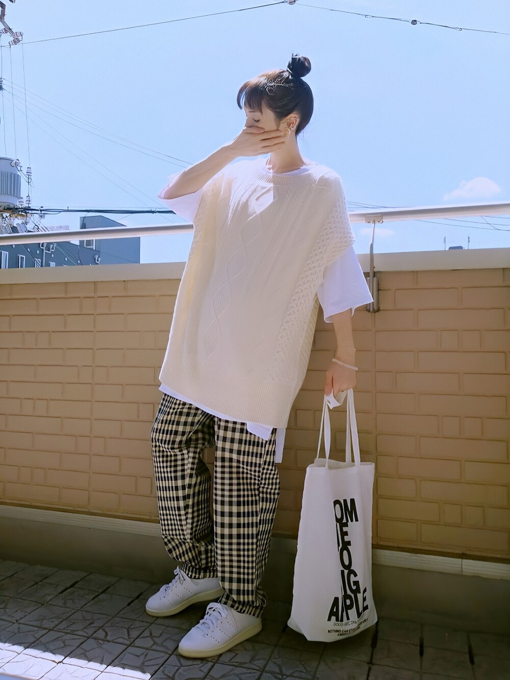 ホワイト系のスニーカー、ベージュ系のベスト、ブラック系のトートバッグを着用したレディースの夏コーディネートの1枚目の写真