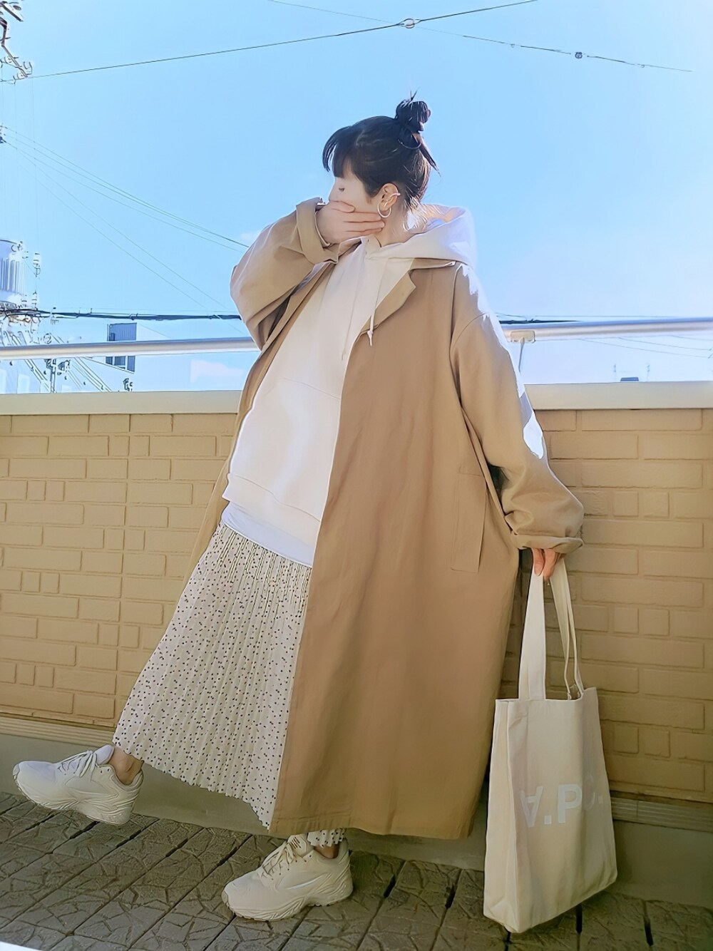 ベージュ系のスニーカー、ベージュ系のチェスターコート、ホワイト系のパーカーを着用したレディースの冬コーディネートの1枚目の写真