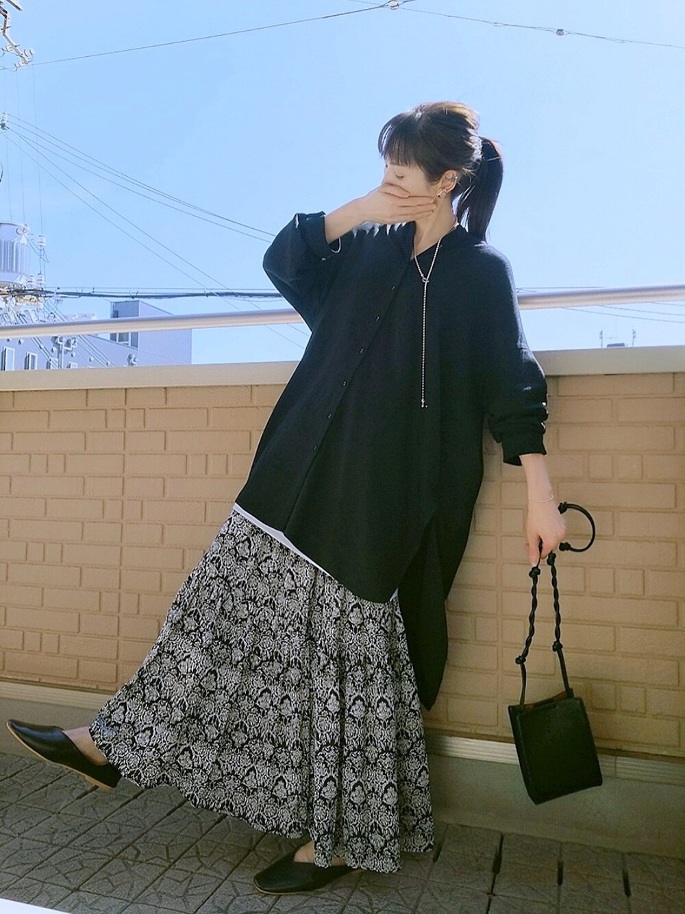 ブラック系のシャツ/ブラウス、ブラック系のスカート、ブラック系のパンプスを着用したレディースの春コーディネートの1枚目の写真