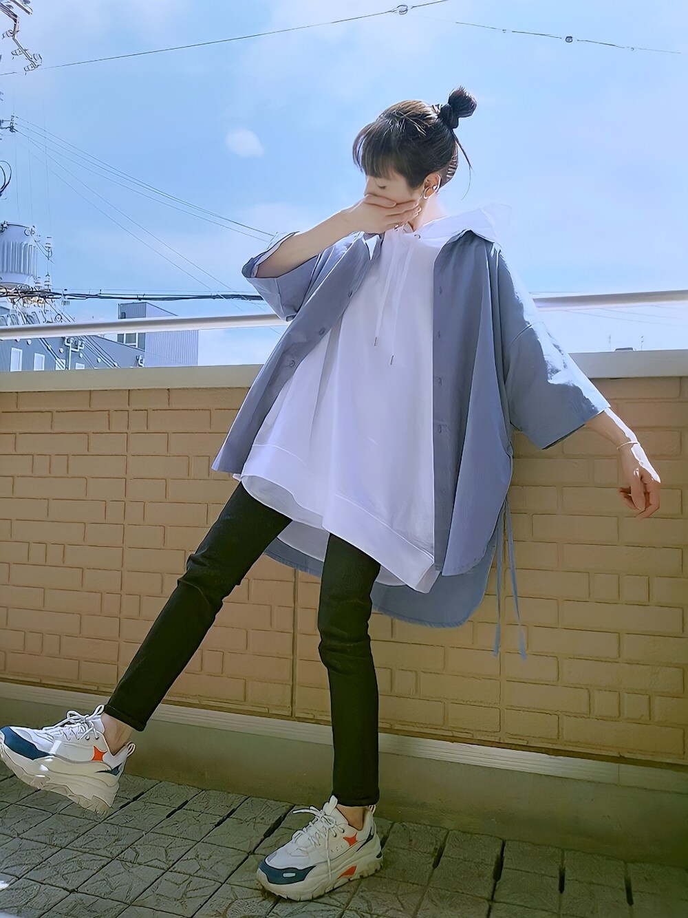 ブラック系のデニムパンツ、ホワイト系のスニーカー、ブルー系のシャツ/ブラウスを着用したレディースの春コーディネートの1枚目の写真