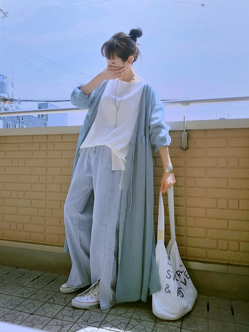 ホワイト系のスニーカー、ホワイト系のショルダーバッグ、ブルー系のデニムパンツを着用したレディースの春コーディネートの1枚目の写真