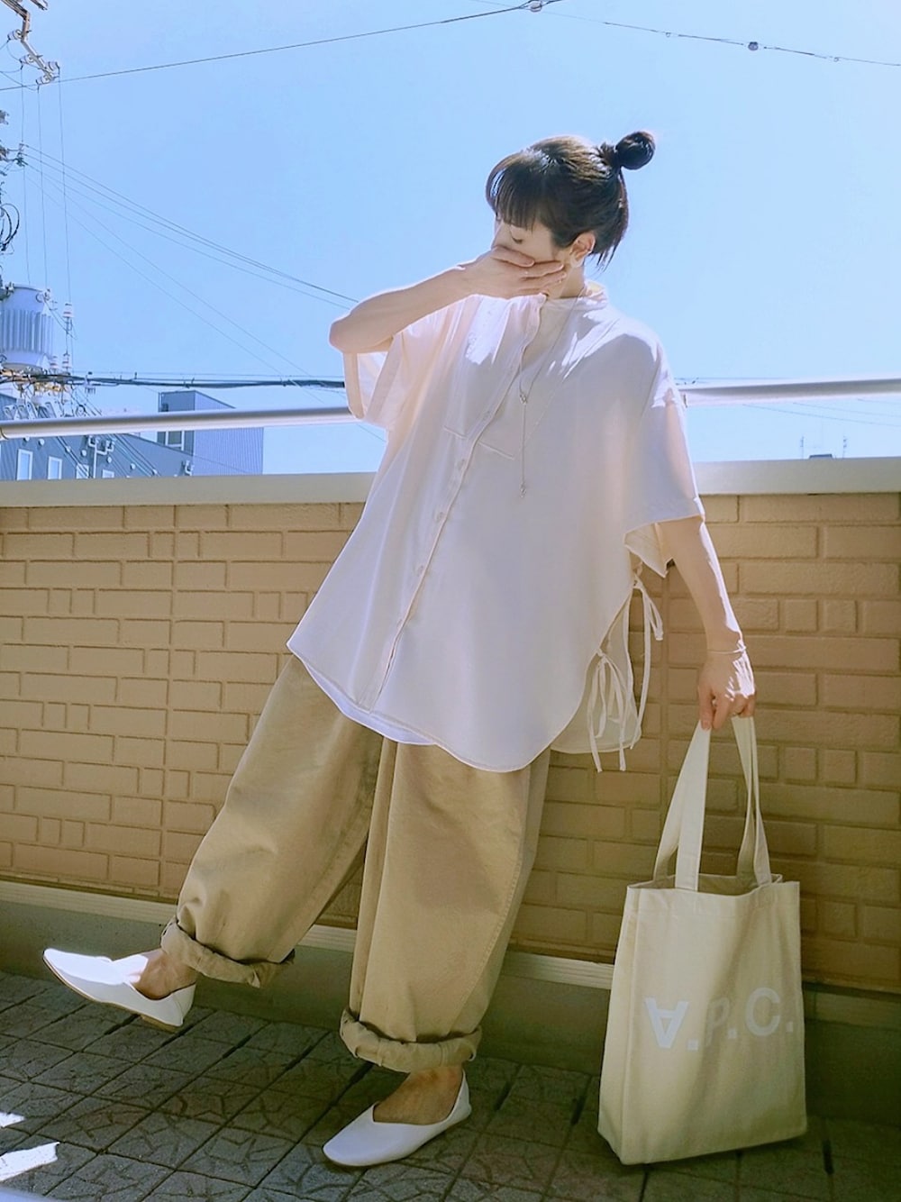 ベージュ系のトートバッグ、ベージュ系のパンツ、ホワイト系のシャツ/ブラウスを着用したレディースの春コーディネートの1枚目の写真