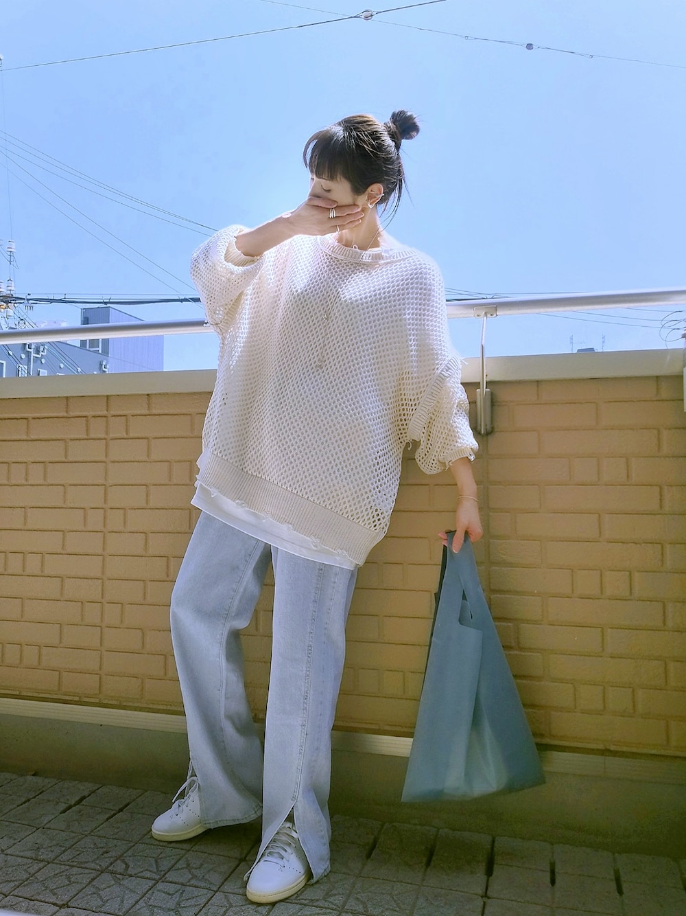 ホワイト系のスニーカー、ブルー系のエコバッグ/サブバッグ、ブルー系のデニムパンツを着用したレディースの春コーディネートの1枚目の写真