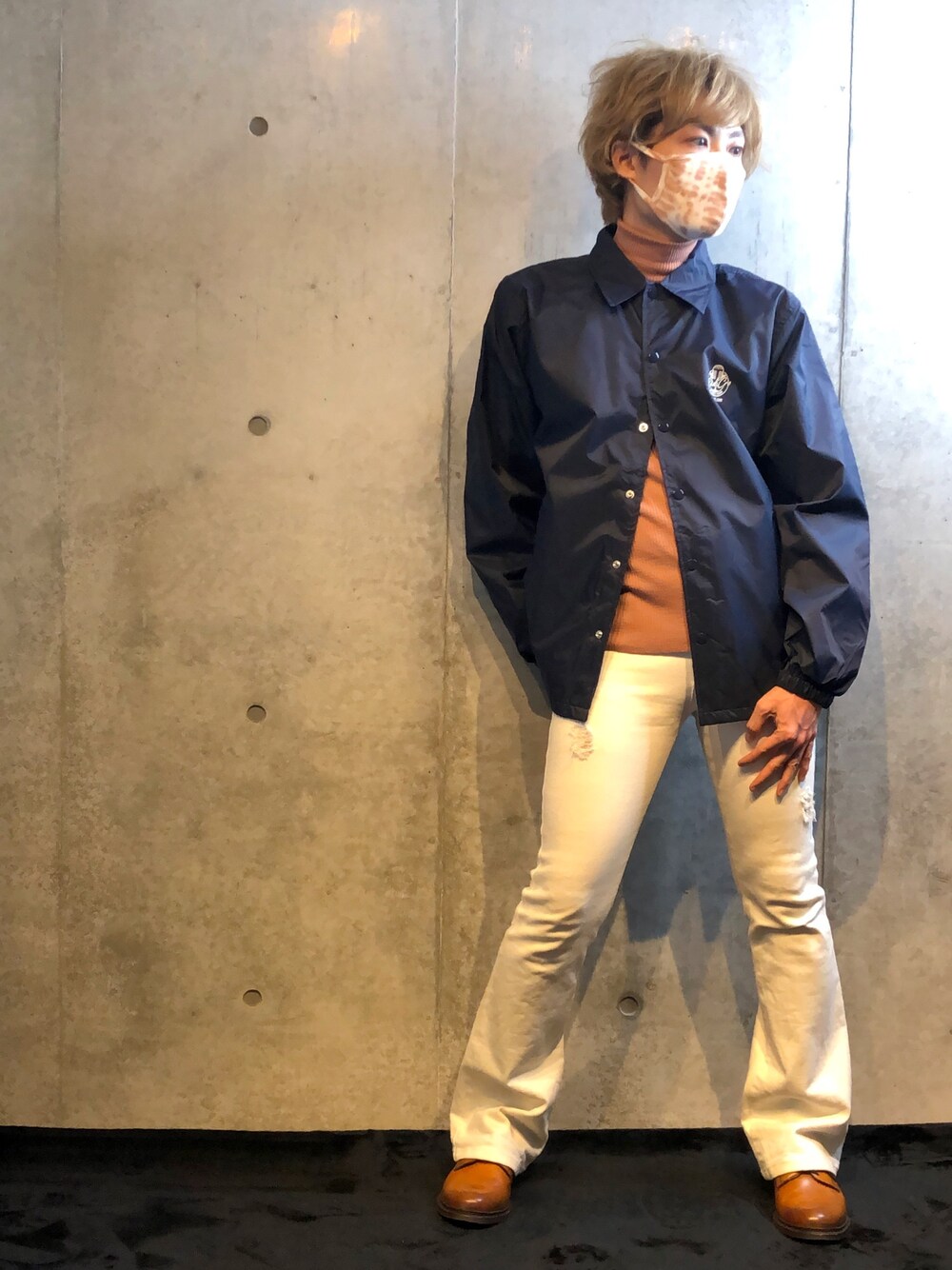 ブルー系のブルゾン、オレンジ系のニット/セーター、ホワイト系のデニムパンツを着用したメンズの秋コーディネートの1枚目の写真