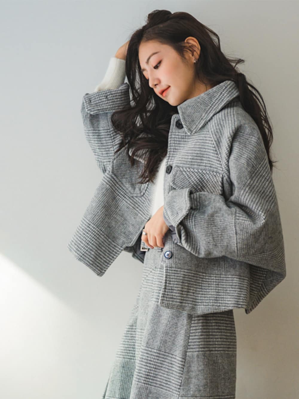 グレー系のセットアップ、ホワイト系のニット/セーターを着用したレディースの秋コーディネートの1枚目の写真