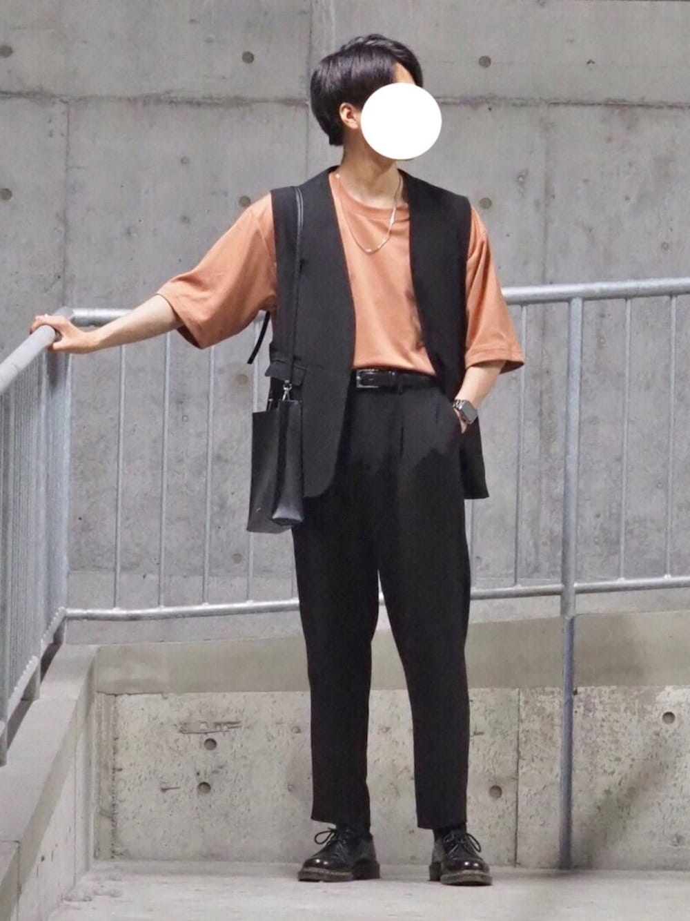 オレンジ系のTシャツ/カットソー、ブラック系のベスト、ブラック系のショルダーバッグを着用したメンズの夏コーディネートの1枚目の写真