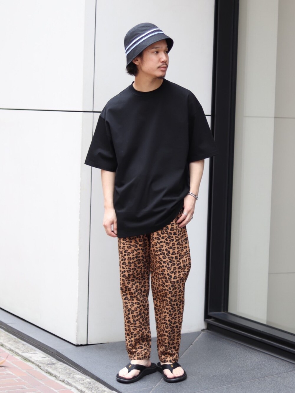 ブラック系のTシャツ/カットソー、ブラウン系のその他パンツ、ブラック系のサンダルを着用したメンズの夏コーディネートの1枚目の写真