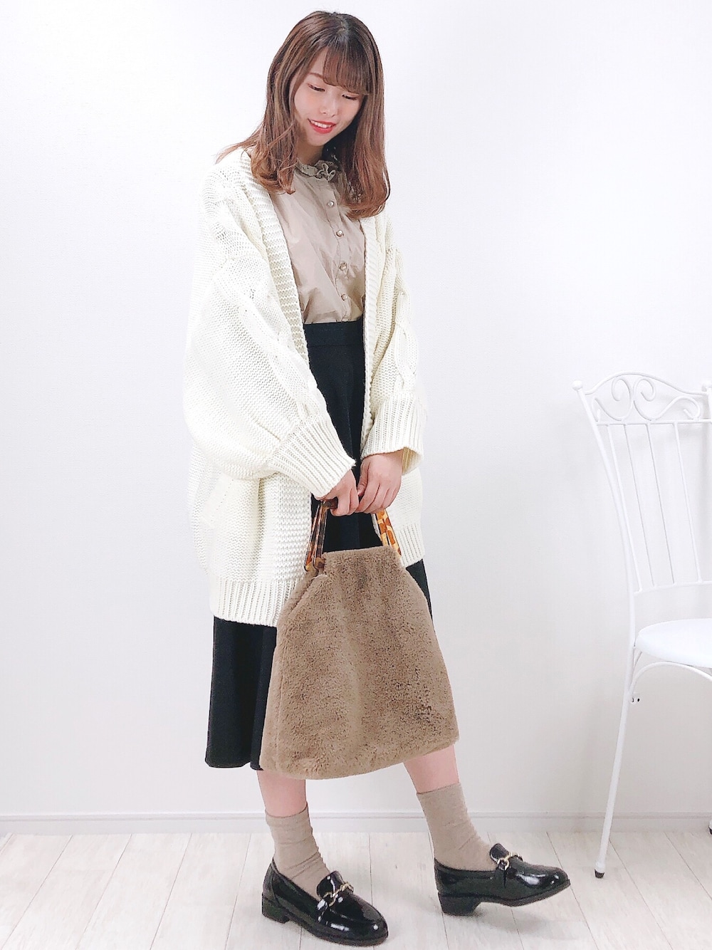 ホワイト系のカーディガン/ボレロ、ベージュ系のシャツ/ブラウス、ブラック系のスカートを着用したレディースの秋コーディネートの1枚目の写真