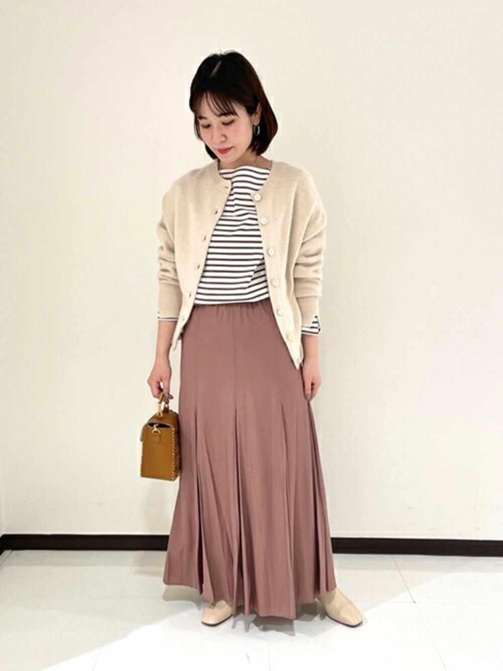 ホワイト系のカーディガン/ボレロ、ブラウン系のTシャツ/カットソー、ピンク系のスカートを着用したレディースの冬コーディネートの1枚目の写真
