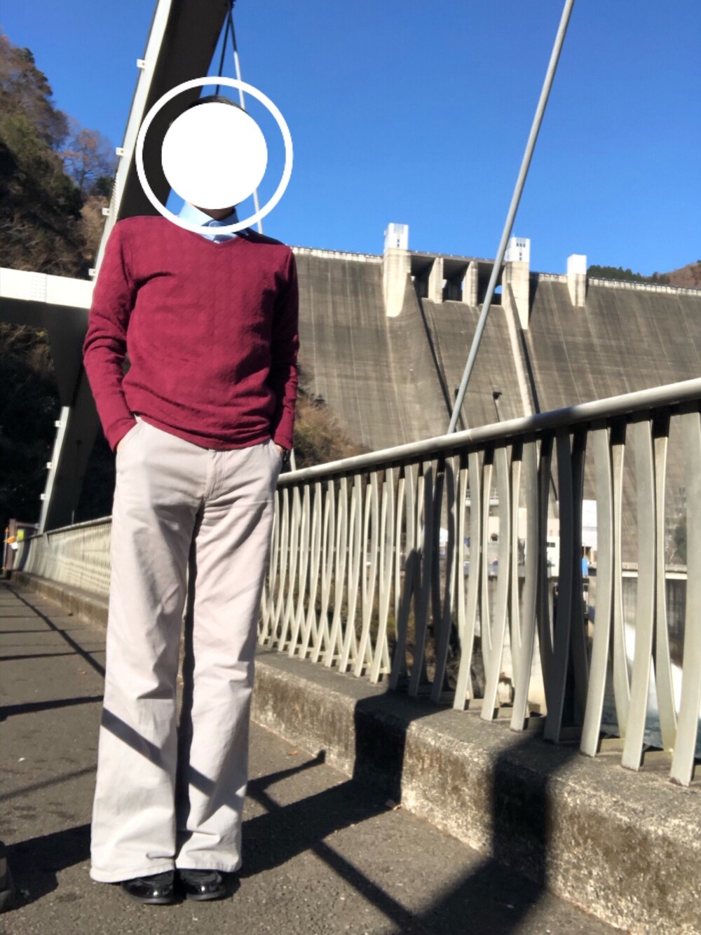 グレー系のパンツ、レッド系のニット/セーター、ブルー系のシャツ/ブラウスを着用したメンズの冬コーディネートの1枚目の写真