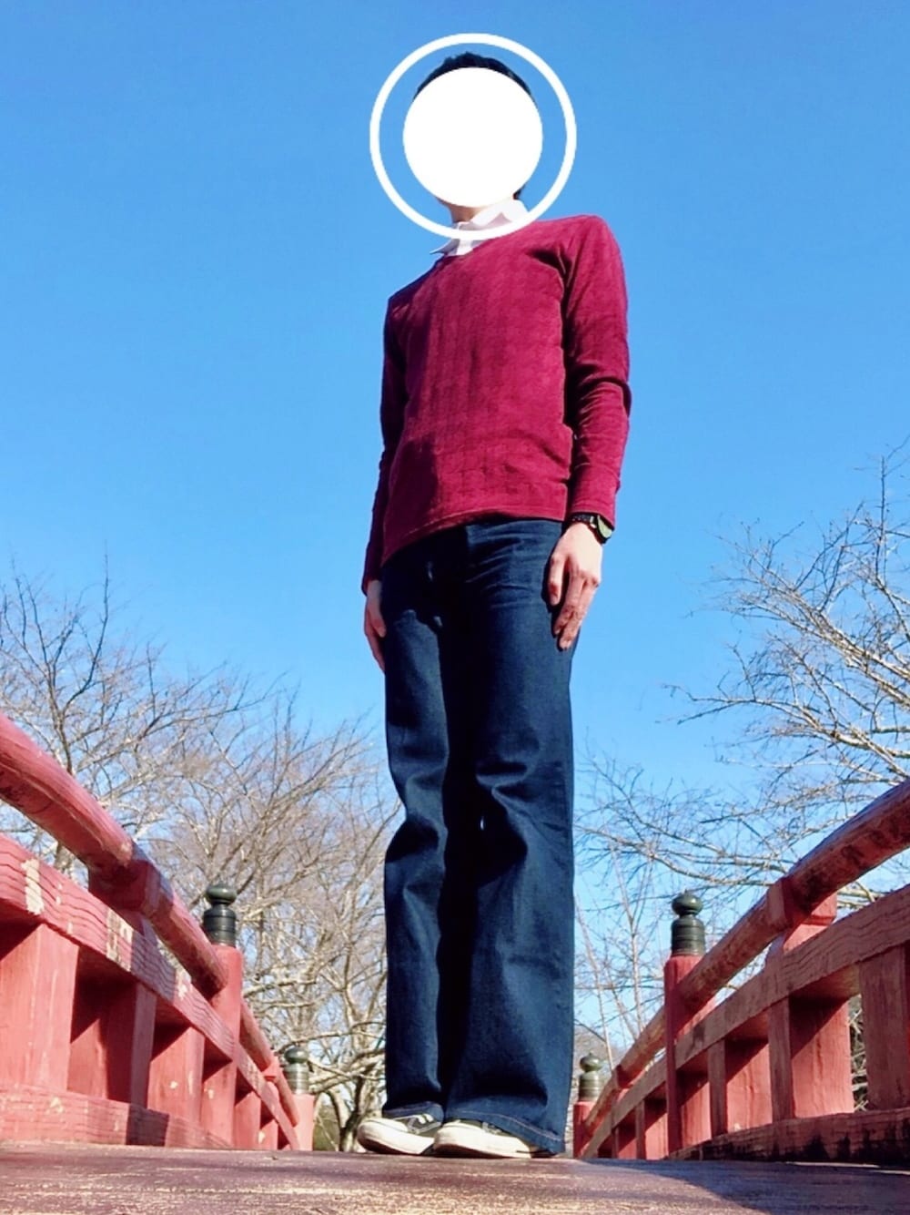 レッド系のニット/セーター、ブルー系のデニムパンツ、ブラック系のスニーカーを着用したメンズの冬コーディネートの1枚目の写真