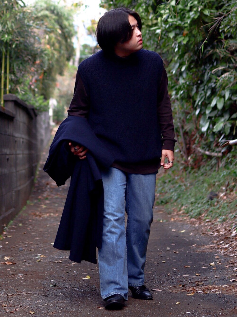 ブルー系のベスト、ブラウン系のTシャツ/カットソー、ブルー系のデニムパンツを着用したメンズの冬コーディネートの1枚目の写真