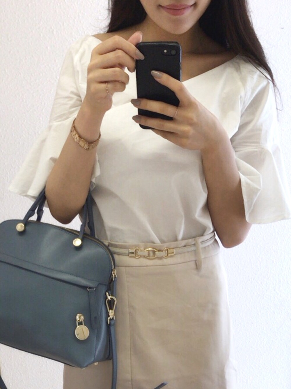 ベージュ系のスカート、ブルー系のハンドバッグ、ホワイト系のシャツ/ブラウスを着用したレディースの夏コーディネートの1枚目の写真