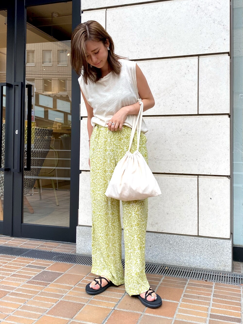 ホワイト系のトートバッグ、グリーン系のその他パンツ、ベージュ系のTシャツ/カットソーを着用したレディースの夏コーディネートの1枚目の写真