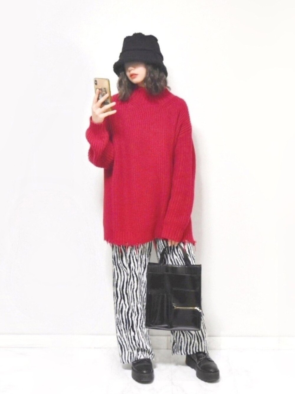 レッド系のニット/セーター、ホワイト系のTシャツ/カットソー、ブラック系のショルダーバッグを着用したレディースの冬コーディネートの1枚目の写真