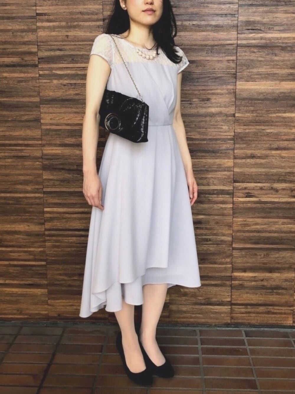 グレー系のドレス、ブラック系のクラッチバッグ、ブラック系のパンプスを着用したレディースの夏コーディネートの1枚目の写真