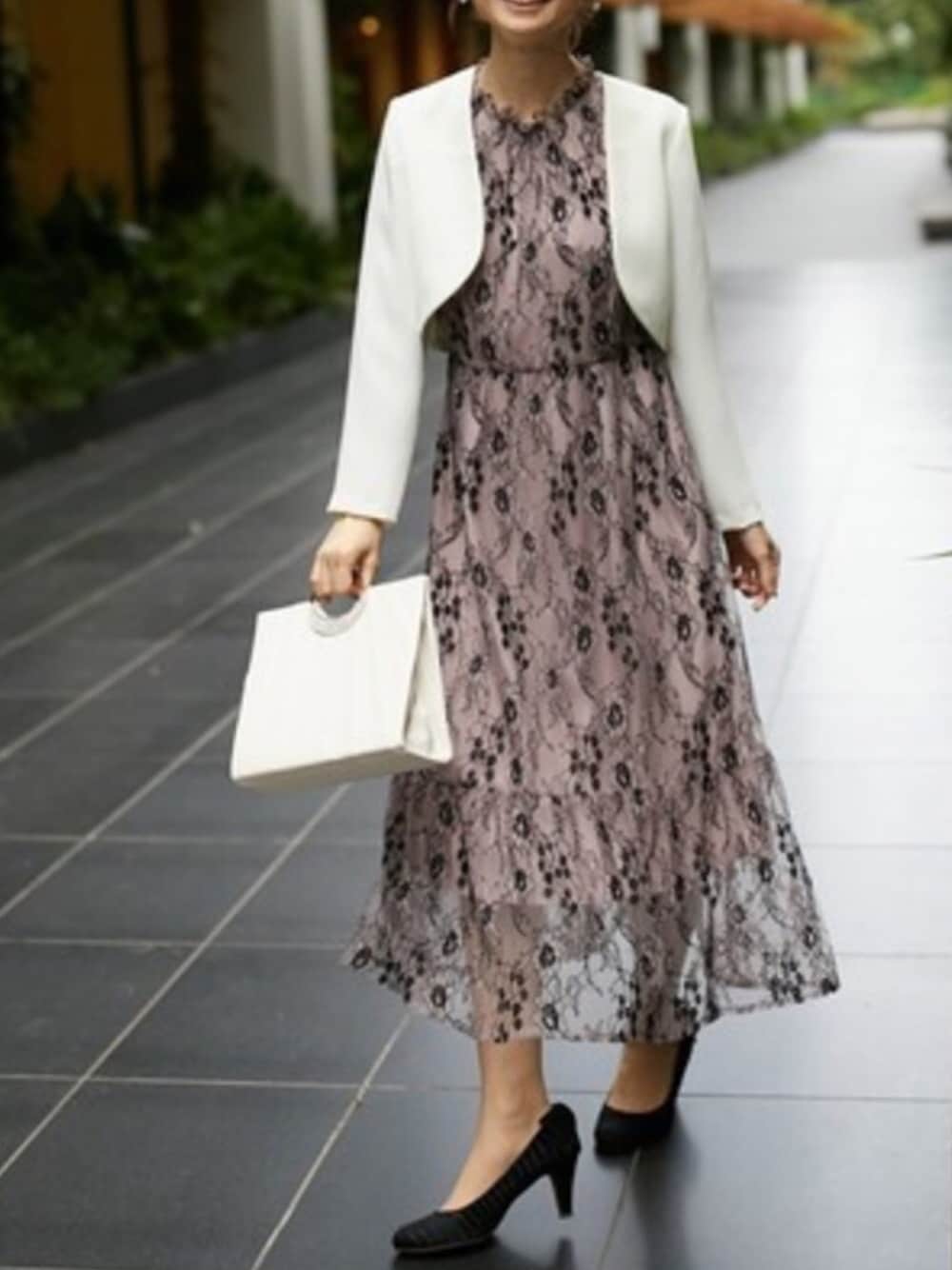 パープル系のドレス、ホワイト系のハンドバッグ、ブラック系のパンプスを着用したレディースの秋コーディネートの1枚目の写真