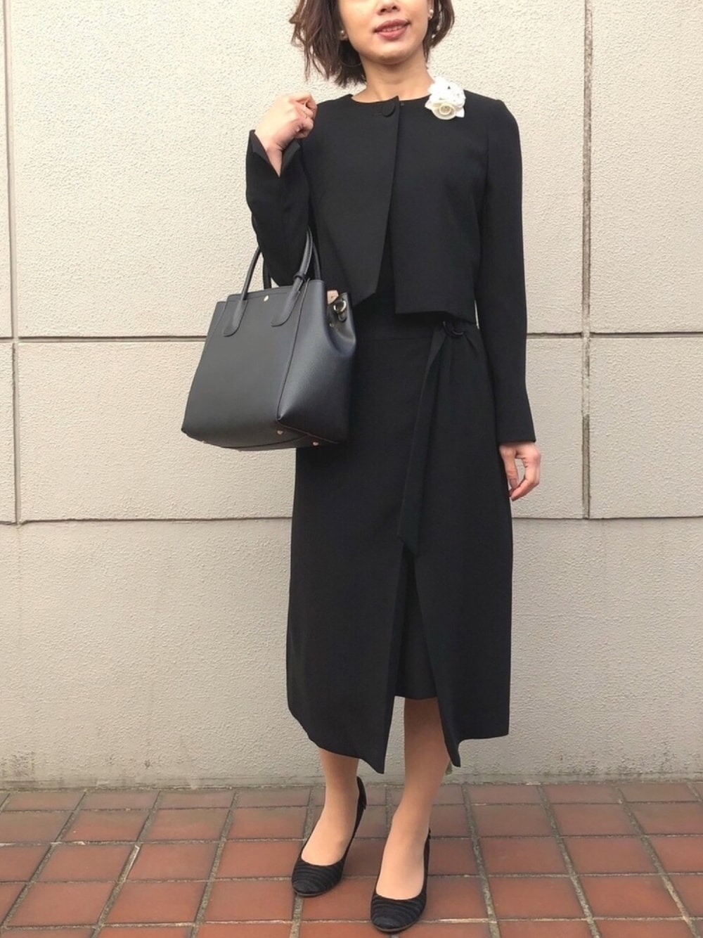 ブラック系のハンドバッグ、ブラック系のスーツセット、ブラック系のパンプスを着用したレディースの冬コーディネートの1枚目の写真