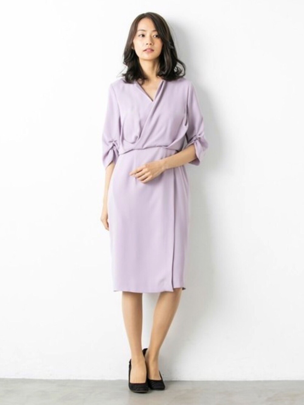 パープル系のドレス、ブラック系のパンプスを着用したレディースの春コーディネートの1枚目の写真