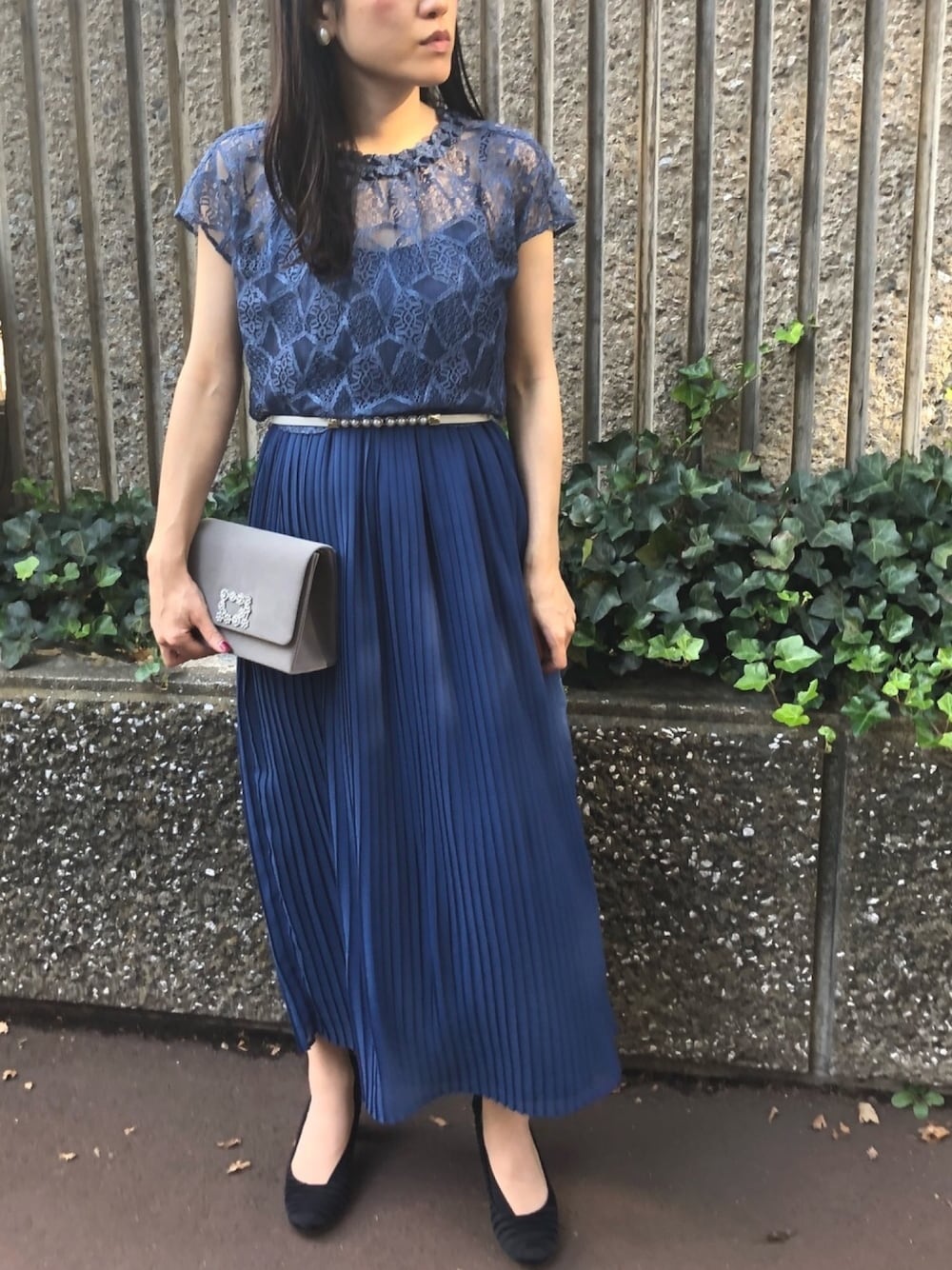 グレー系のクラッチバッグ、グレー系のベルト、ホワイト系のイヤリングを着用したレディースの夏コーディネートの1枚目の写真