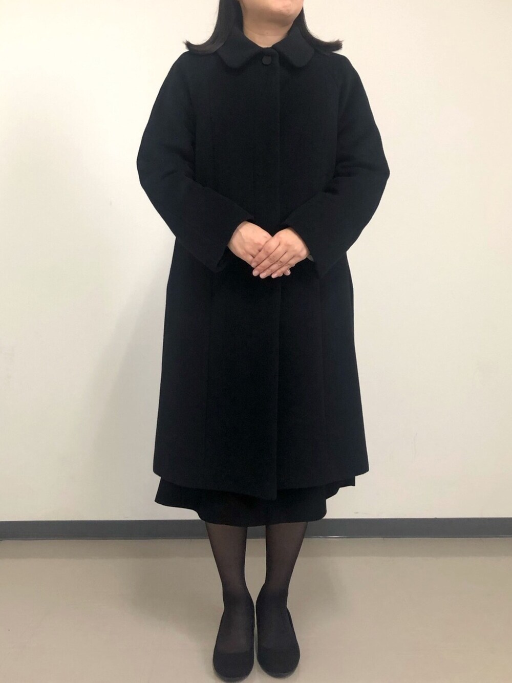 ブラック系のステンカラーコートを着用したレディースの秋コーディネートの1枚目の写真